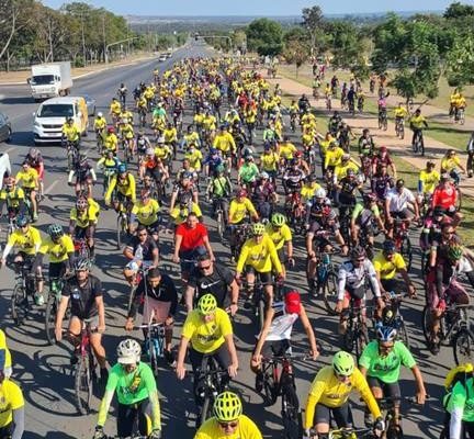 foto colorida vertical de centenas de ciclistas vestidos com roupas amarelos, verdes e vermelhas