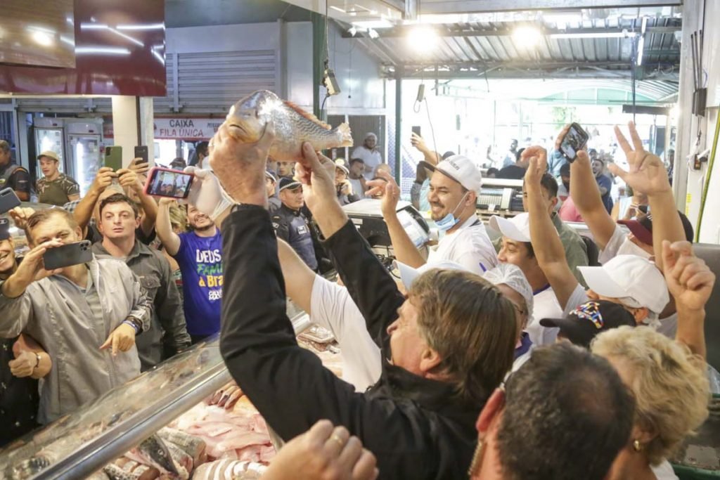 presidente jair bolsonaro levanta um peixe e tira foto com apoiadores
