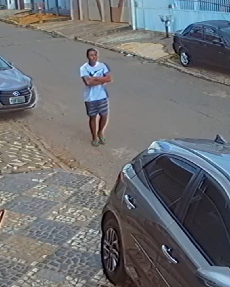 Ladrão de camisa azul caminhando em direção à vítima