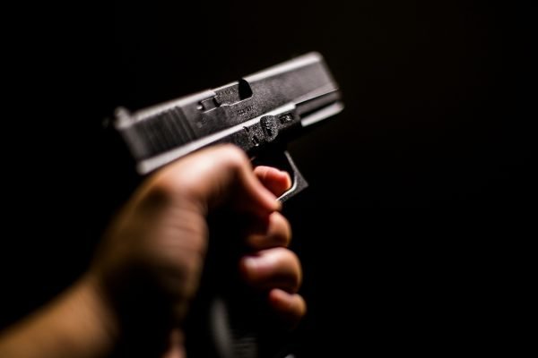 foto mostra uma mão masculina segurando uma arma de fogo