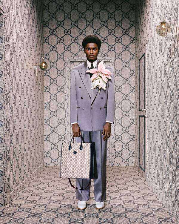 Modelo usa terno Gucci com monograma e flor gigante no bolso do paletó