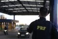 Homem de costas com farda. Carro passando na pista ao fundo
