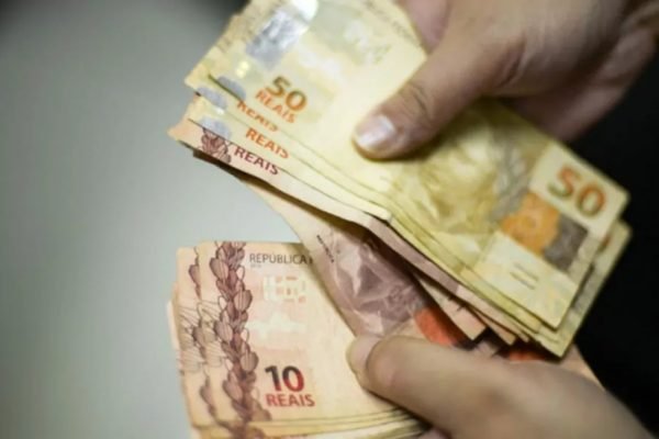 uma mão segura várias notas de 10 e 20 reais