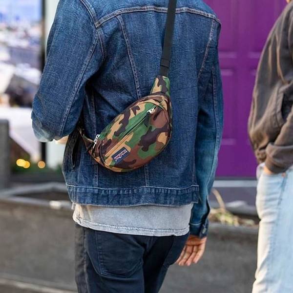 Homem usa pochete com estampa militar sob uma jaqueta jeans 