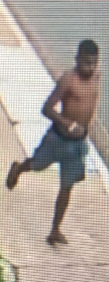 Homem negro, sem camisa, de bermuda e chinelo, corre na calçada