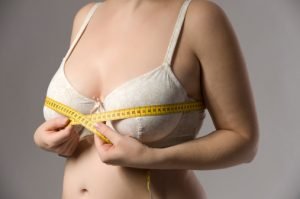 mulher medindo o tamanho dos seios com uma fita métrica