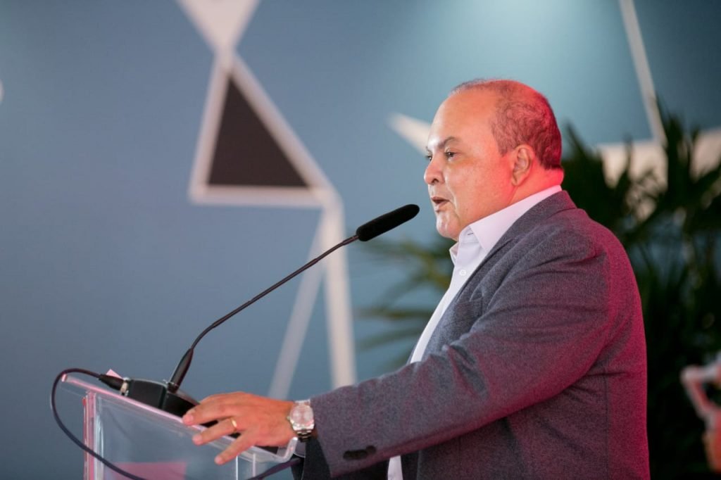 Fotografia colorida de homem de terno discursando em microfone