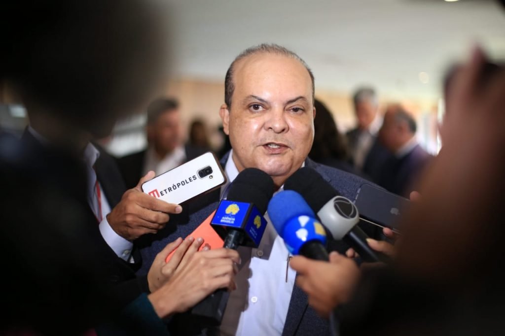 Fotografia colorido de um homem falando em vários microfones
