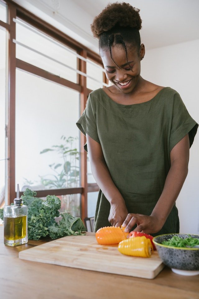 Mulher jovem cortando vegetais em cozinha