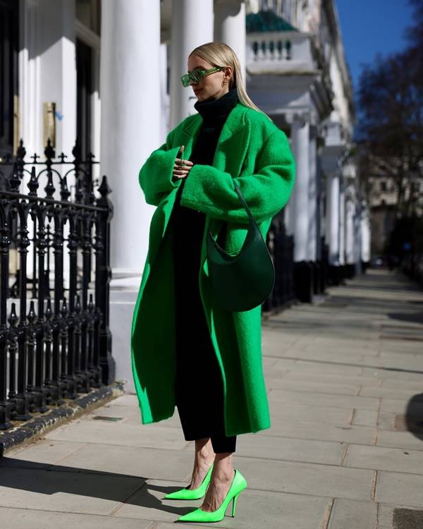 mulher loira usa casaco, sapato e bolsa verde