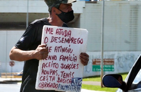 homem segura cartaz na rua com pedido de ajuda