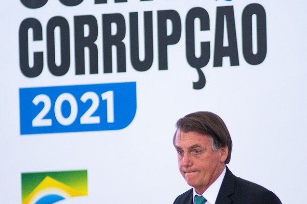 Jair Bolsonaro é fotografado em frente a um painel que diz