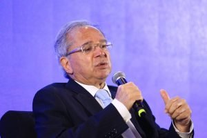 O ministro da economia, Paulo Guedes, discursa segurando um microfone. Ele usa terno e gravata - Metrópoles