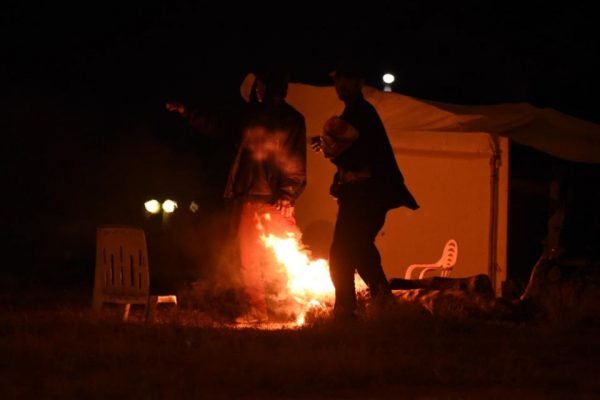 silhuetas se abrigam perto de fogo