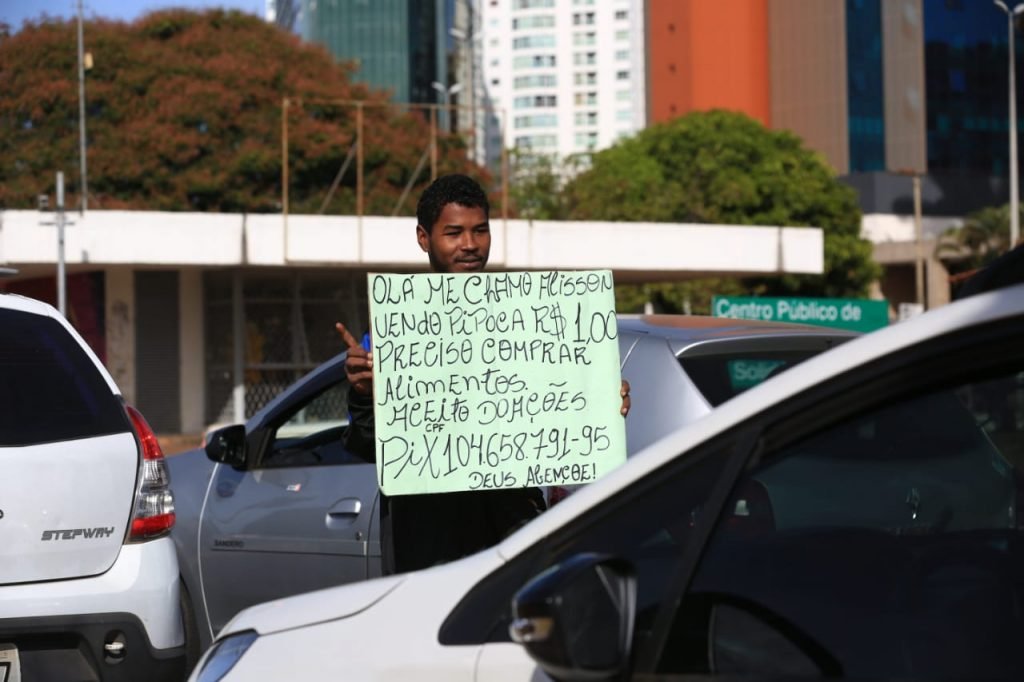 Homem segurando uma placa pedindo doações