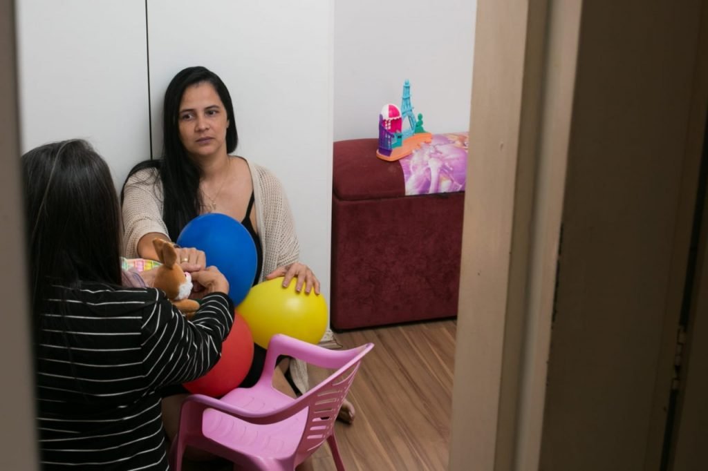 Claudete sentada no chão segurando a mão da sogra