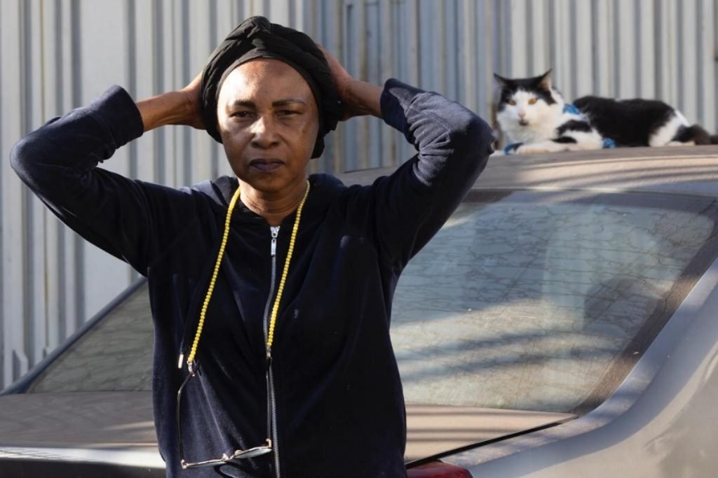 mulher com as mãos na cabeça e um gato atrás