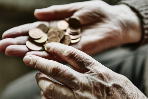 mãos de uma pessoa idosas seguram moedas
