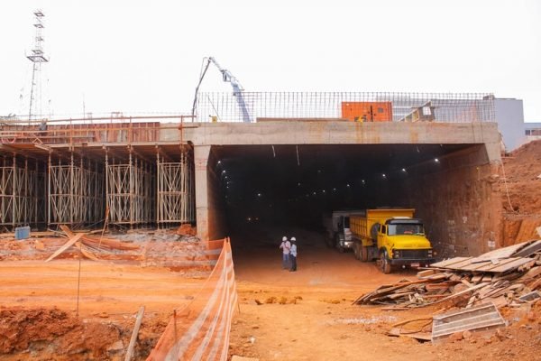 Homens conversam diante de abertura de túnel