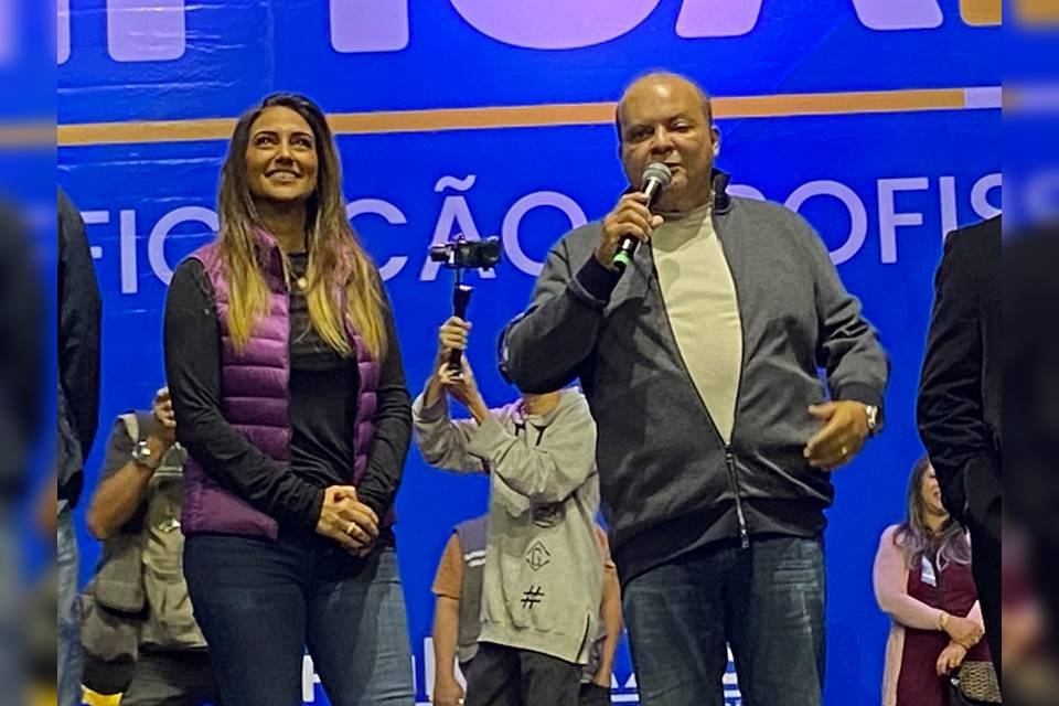 Uma mulher e um homem em frente a um telão azul
