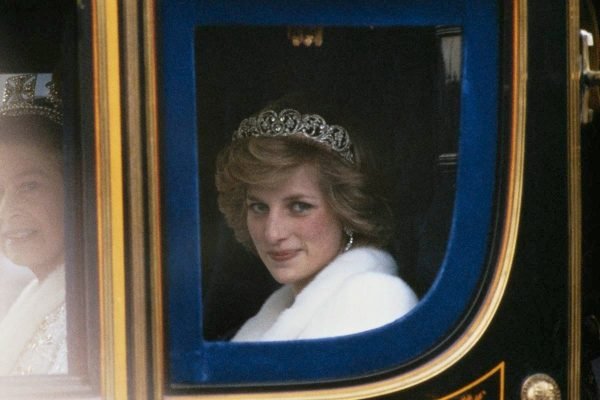 Mulher branca dentro de um carro com uma tiara de diamantes na cabeça