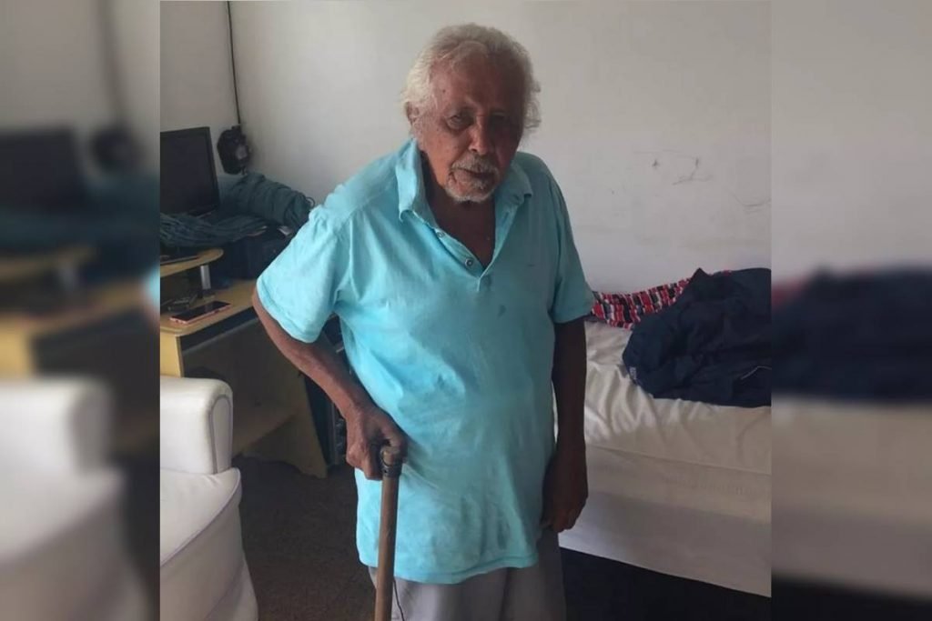 Idoso com camisa azul e bengala na mão