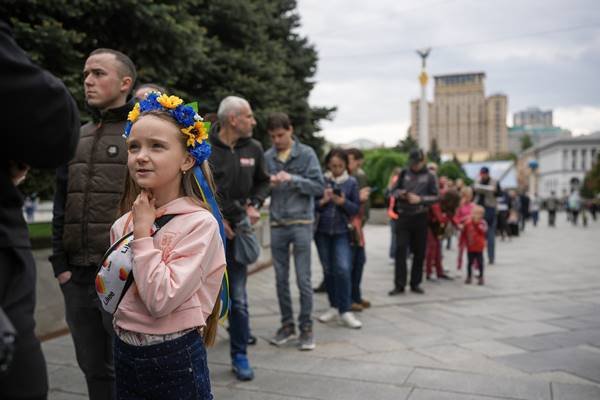 Menina com coroa de flores nas cores da Ucrânia em uma fila