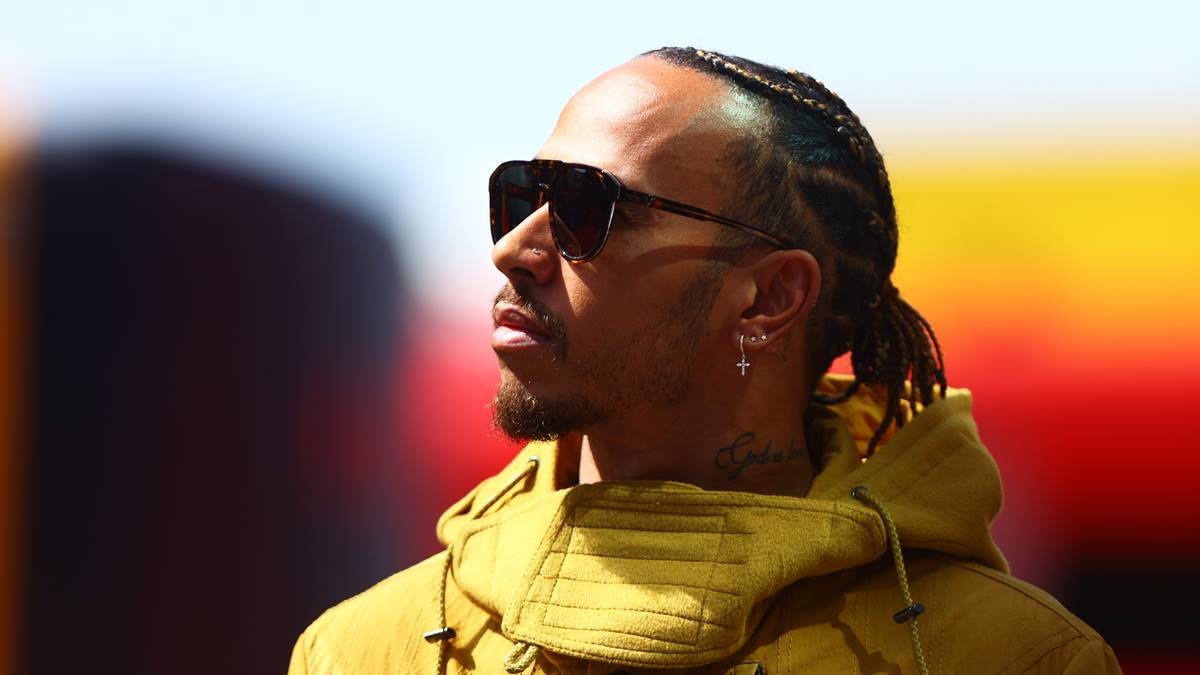 Lewis Hamilton usa casaco amarelo e óculos escuro