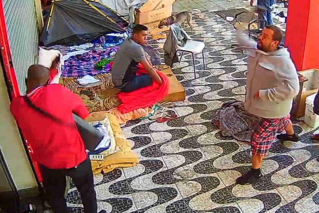 homem de casaco cinza joga objeto em cima de pessoa de casaco vermelho