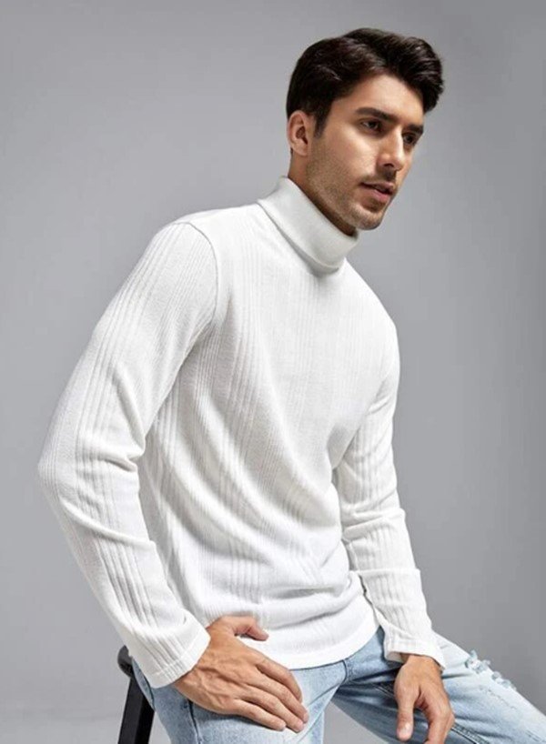 Modelo branco com cabelos castanhos curtos, posando para foto com roupa da marca Shein. Ele estã em um fundo cinza e veste uma blusa de mangas cumpridas e gola alta branca