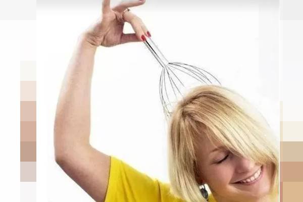 Fotografia colorida de uma mulher segurando um massageador sobre a própria cabeça