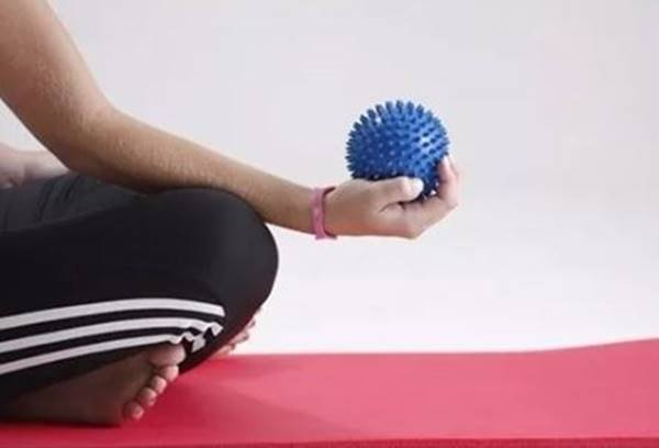Fotografia colorida de pessoa sentada com mão segurando bola emborrachada