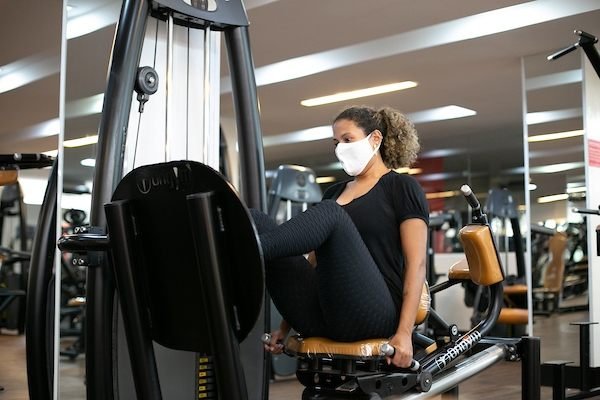 fotografia colorida de mulher em aparelho de academia leg press