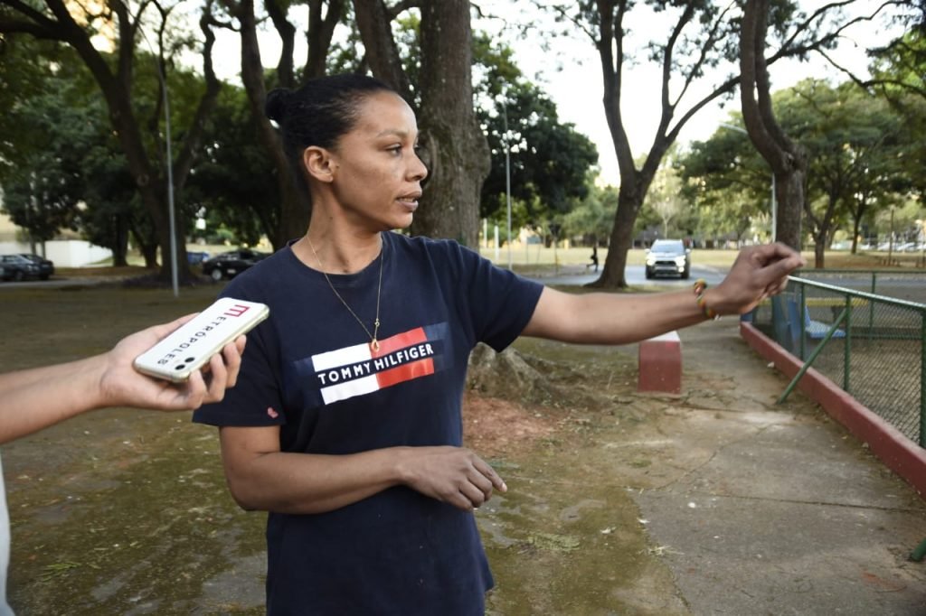 Mulher de camiseta azul mostra parquinho onde foi atacada em tentativa de sequestro de criança em Brasília - Metrópoles
