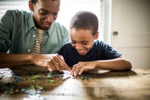 Foto mostra pai e filho resolvendo um quebra-cabeças