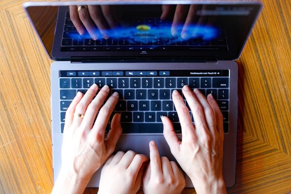 duas pessoas digitam em teclado de notebook