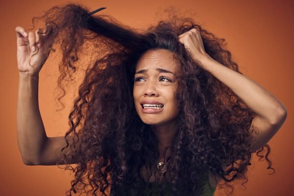 fotografia de mulher escovando cabelo cacheado e com fios embaraçados