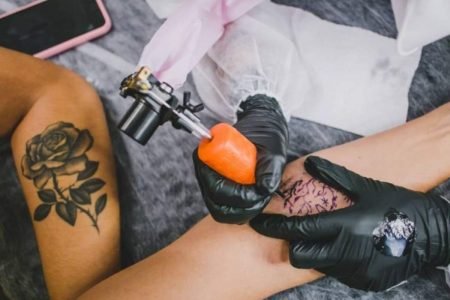 Foto colorida de pessoa sendo tatuada no braço - Metrópoles