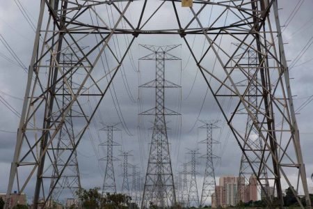 Linhas de transmissão de energia em horizonte com cidade ao fundo - Metrópoles