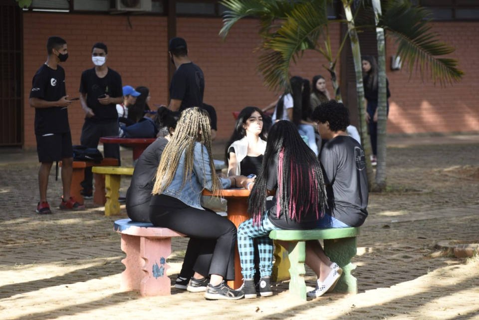 estudantes em sentados em volta de mesa no pátio