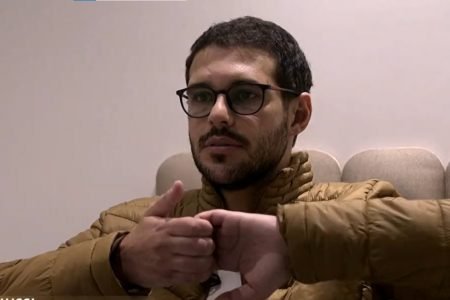 O ex-BBB22 Rodrigo Mussi em sua primeira entrevista após sofrer acidente de trânsito. Ele usa óculos, casaco, é branco e tem barba e cabelo preto curto - Metrópoles