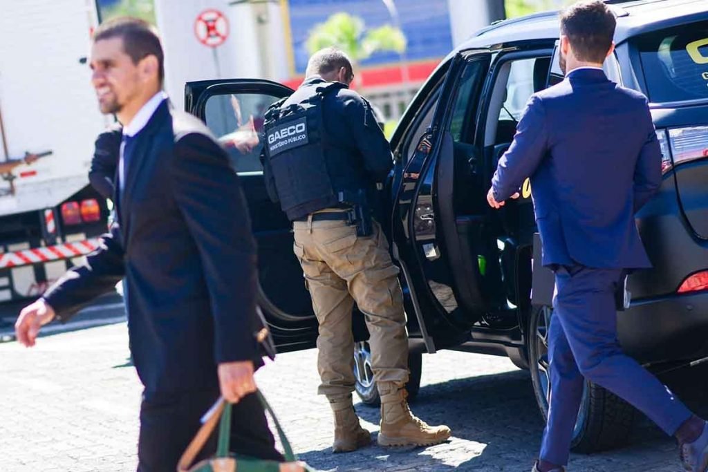 homens com uniformes policiais entrando em carro preto