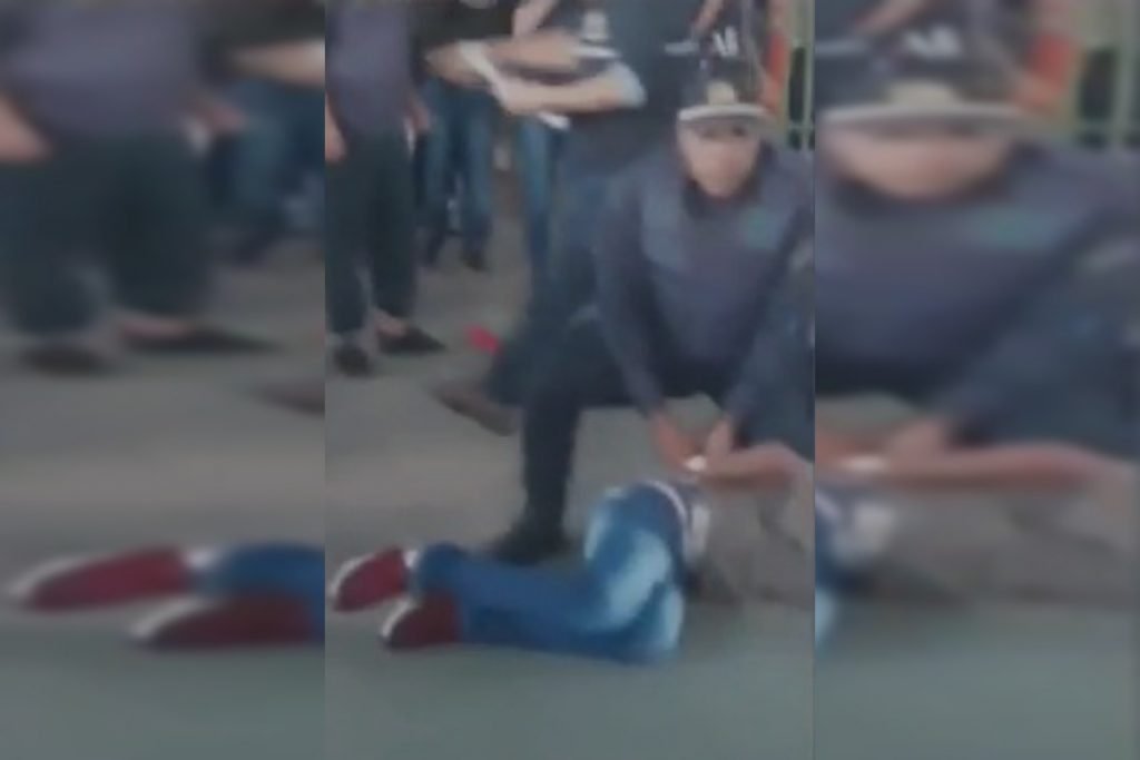 Policial militar ajoelha-se em cima de adolescente