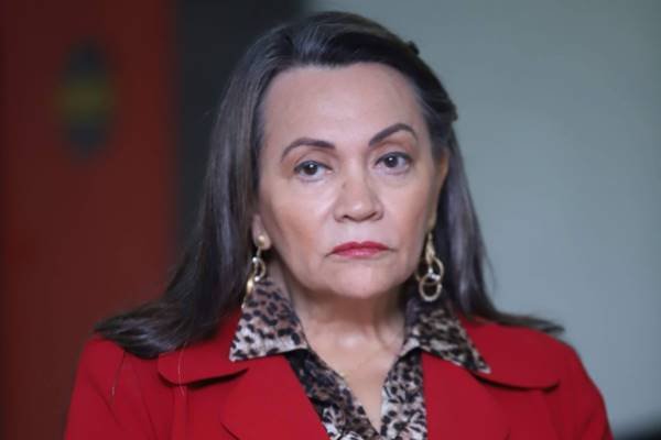 Fotografia colorida de mulher com camisa de onça e blazer vermelho