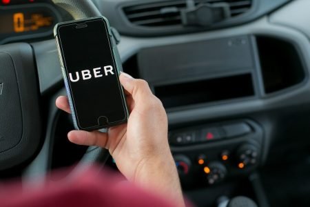 homem segura celular dentro de carro com aplicativo uber