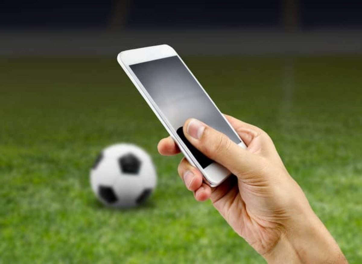 Apostas desportivas online. celular com campo de futebol na tela e