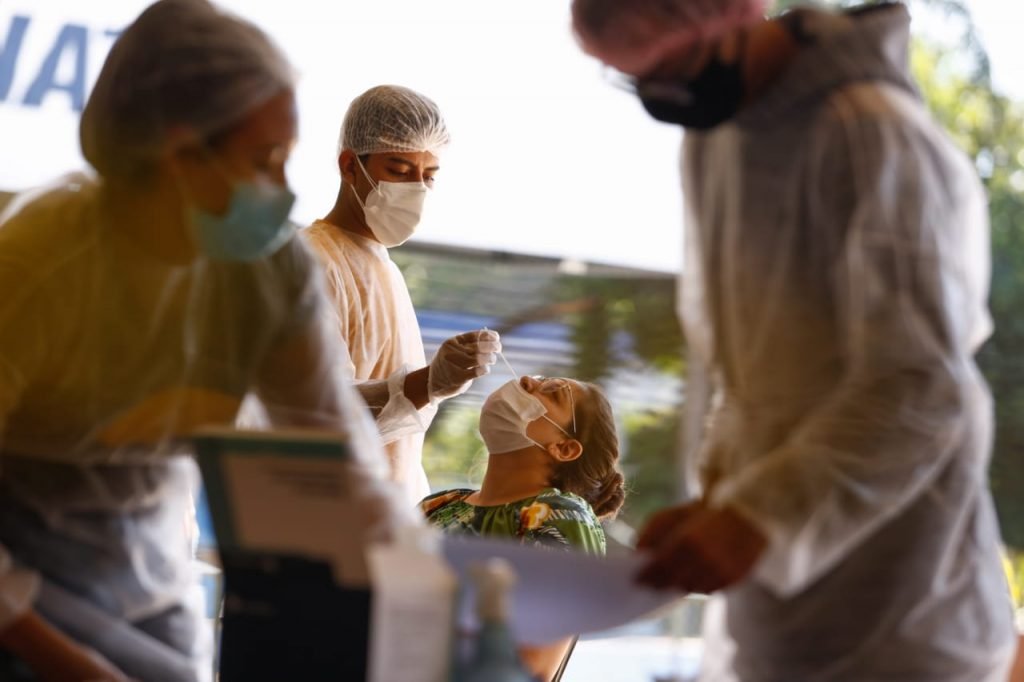 Imagem colorida mostra enfermeiro realizando teste de Covid em paciente - Metrópoles
