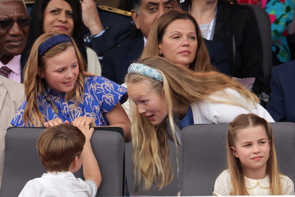 Foto colorida. Savannah tenta entreter o príncipe George. Ao lado, Mia Grace e princesa Charlotte