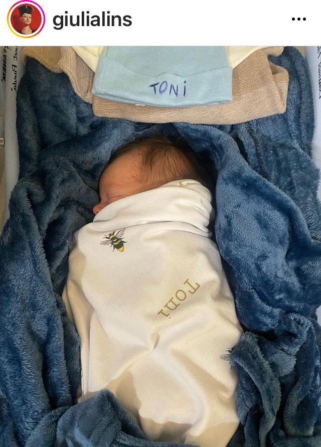 foto colorida de um bebê enrolado em um lençol branco