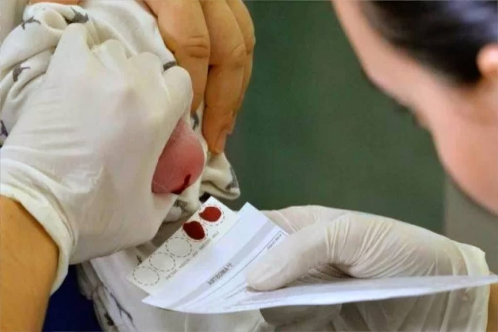 Foto de um pé de um bebê sendo furado para detectar doenças